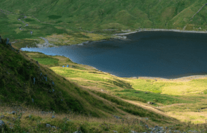 A serene lake surrounded by lush green hills in a picturesque valley.