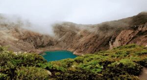 What are Sustainable & Eco-Friendly Destinations? A tranquil blue lake sits in the center of a volcanic crater, with dramatic cliffs rising around its perimeter.