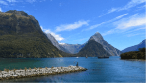 Scenic view of Milford Sound, New Zealand, showcasing towering cliffs and lush greenery against a serene waterway.