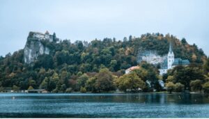 What are Sustainable & Eco-Friendly Destinations? Scenic view of Lake Bled in Slovenia, featuring a church on an island and a castle on a cliff overlooking the water.